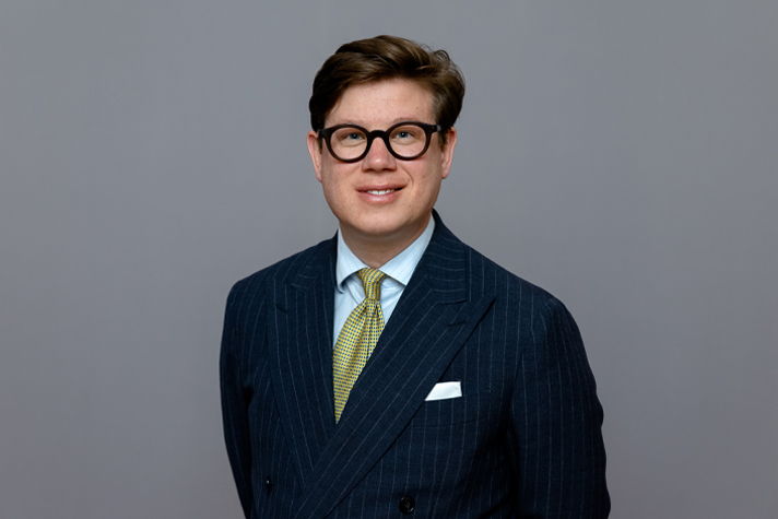 The image shows State Secretary David Sikström wearing a blue blazer against a gray background.