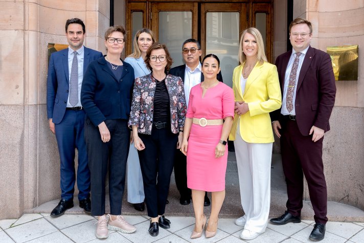 Eight women and men standing in front of a buildnings entrance for a group photo.