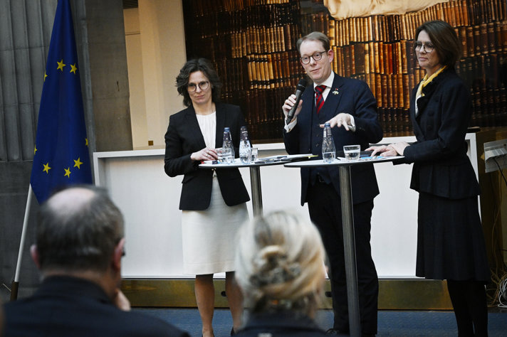 Billström and Roswall standing at a podium speakaing to the audience